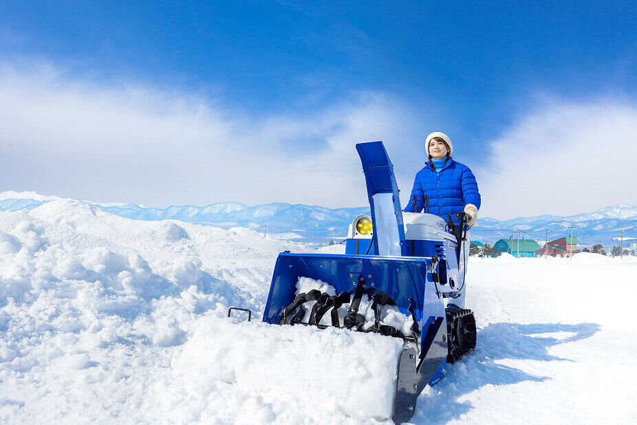 除雪機で女性が雪を集めている写真