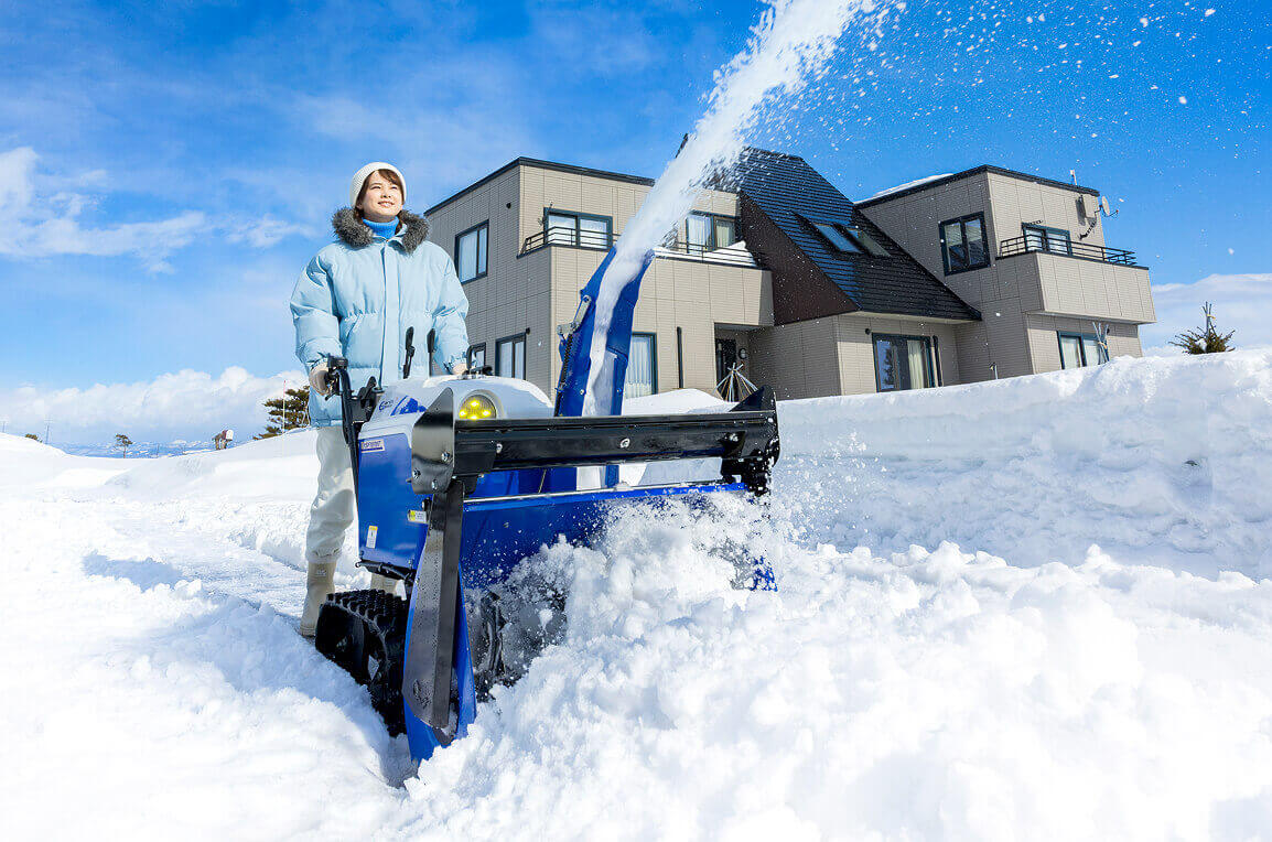 女性がロータリー除雪で雪を飛ばしている写真