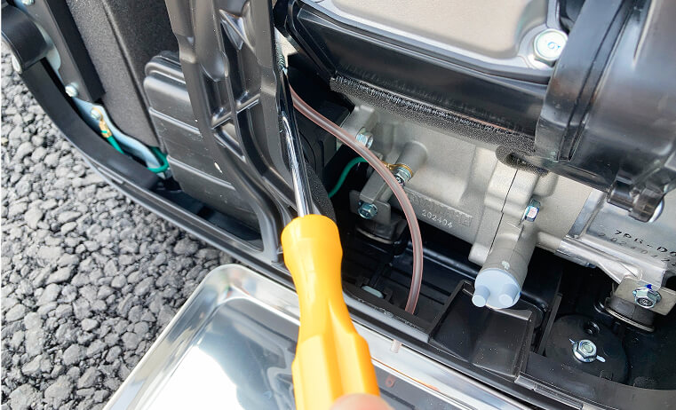 Photo of loosening the drain screw with a Phillips screwdriver